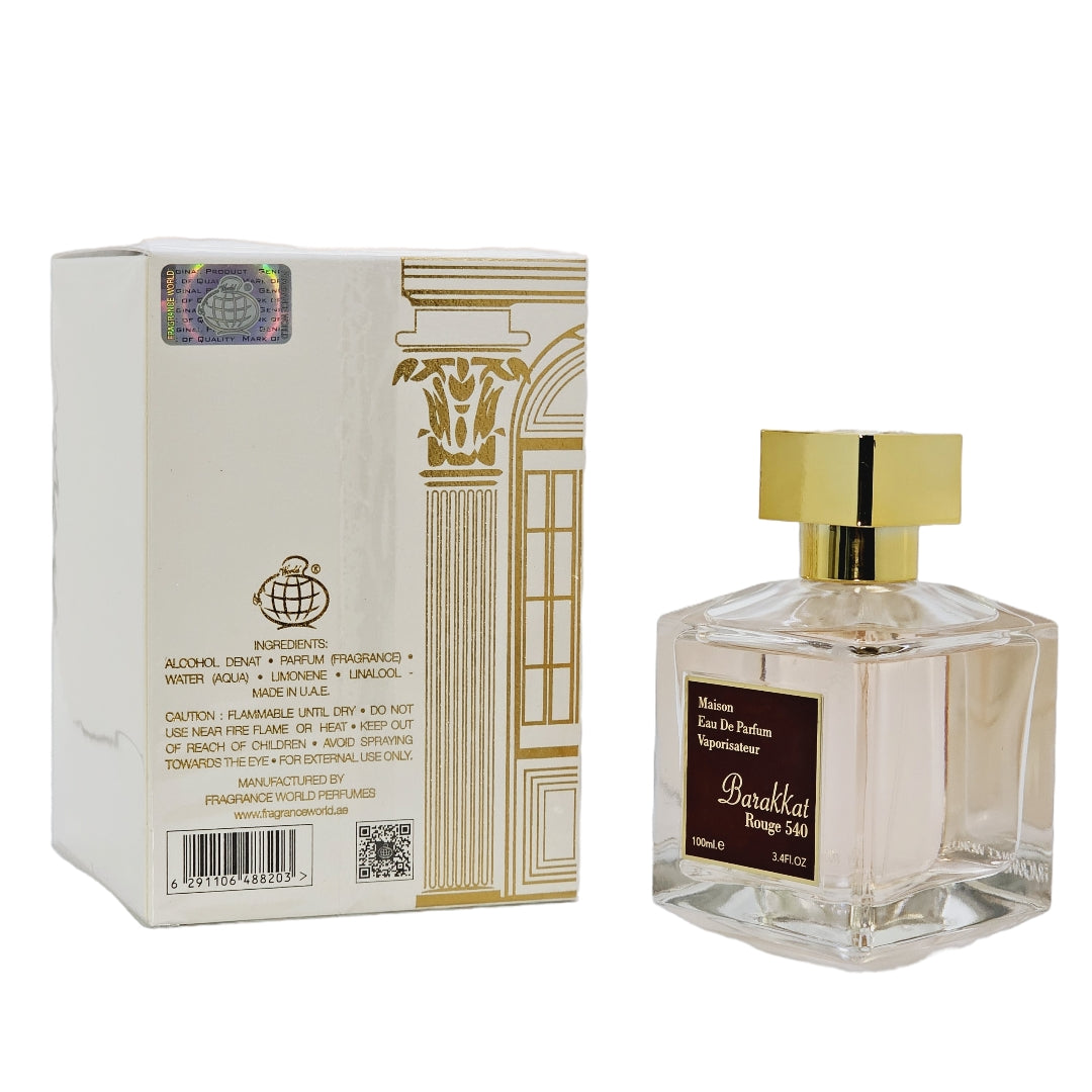 A bottle of Barakkat Rouge 540 Unisex Eau De Parfum with its packaging box. The bottle is clear, showing the light amber-colored perfume liquid, and the box is adorned with gold and brown designs indicating the luxury brand 'Maison'.