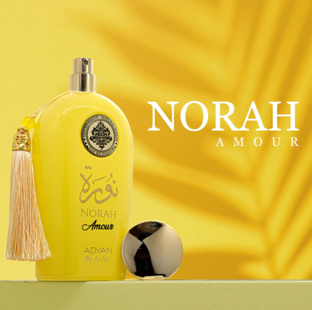 A yellow bottle of Norah Amour Eau de Parfum with a tassel and a black sphere decoration in front, set against a yellow background with a leaf motif in the upper right corner.